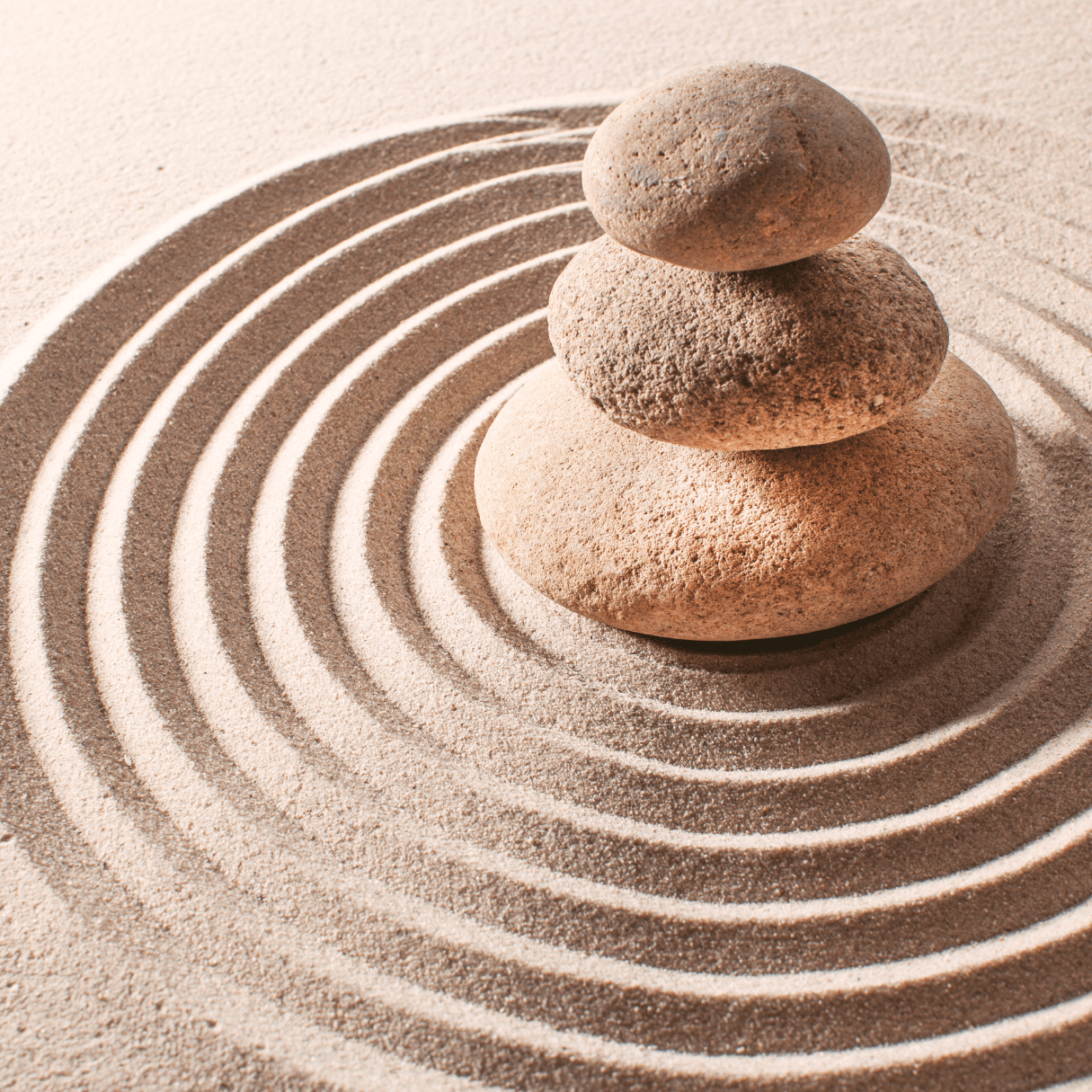 Image shows 3 meditation stones in sand in a circular, zen formation.