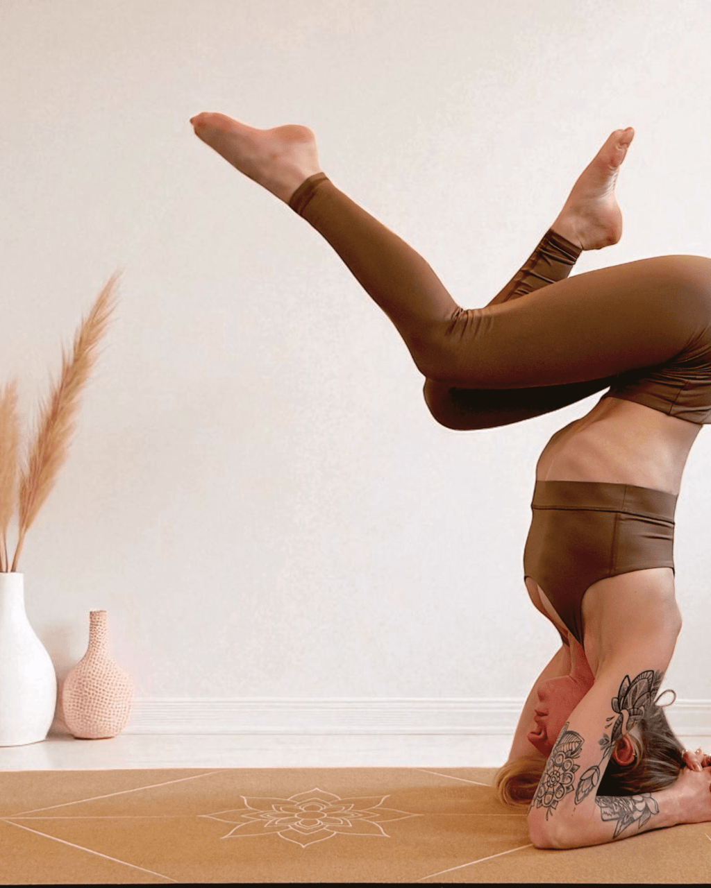 Person performing a yoga pose on a cork yoga mat with decorative vases in the background.