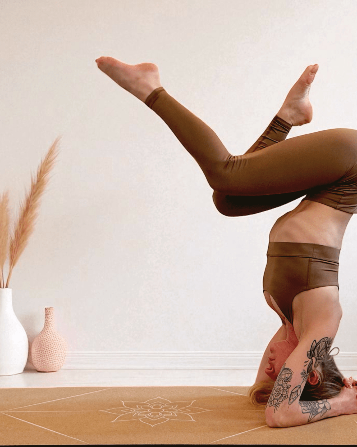 Person performing a yoga pose on a cork yoga mat with decorative vases in the background.