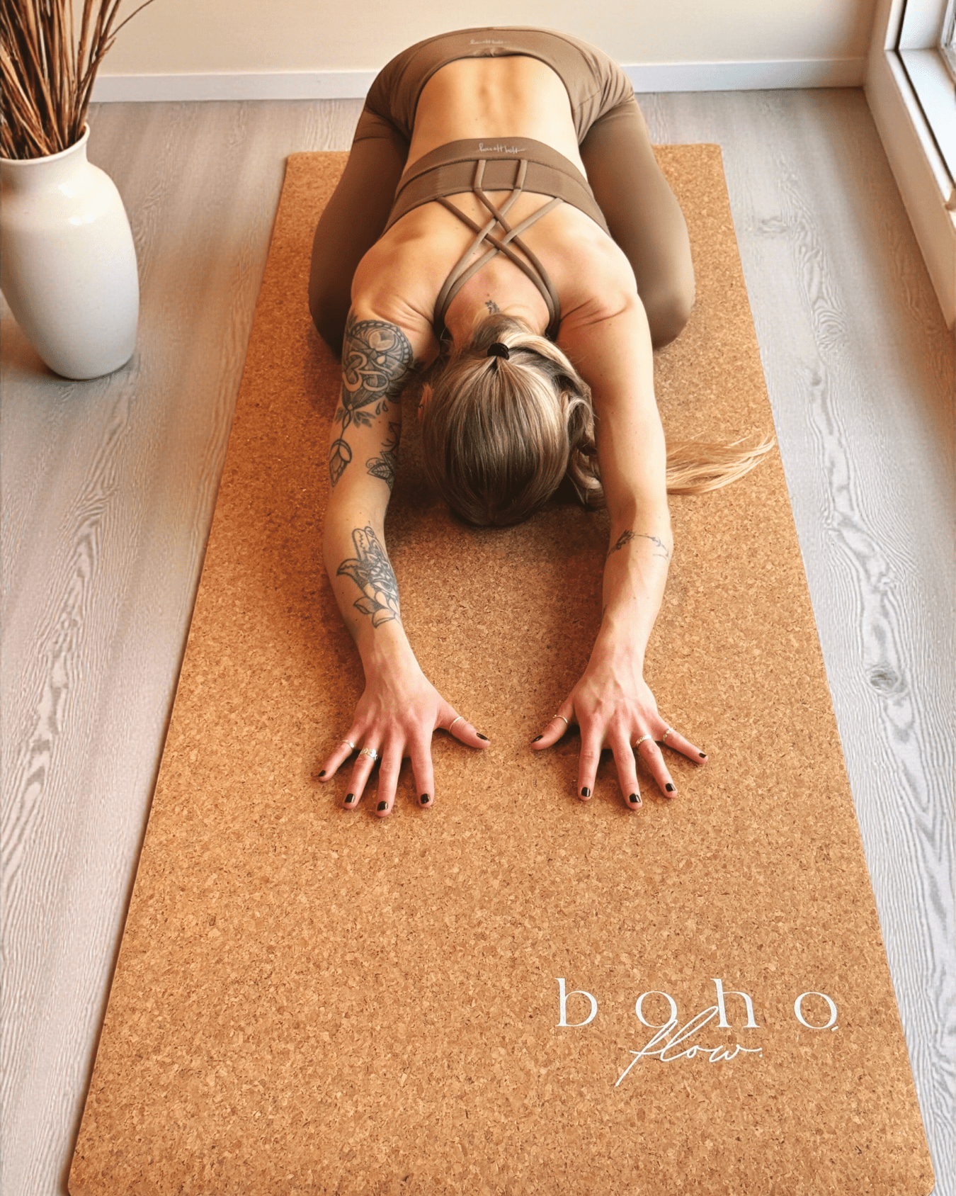Person practicing yoga on a gold and cork mat with 'boho flow' branding.