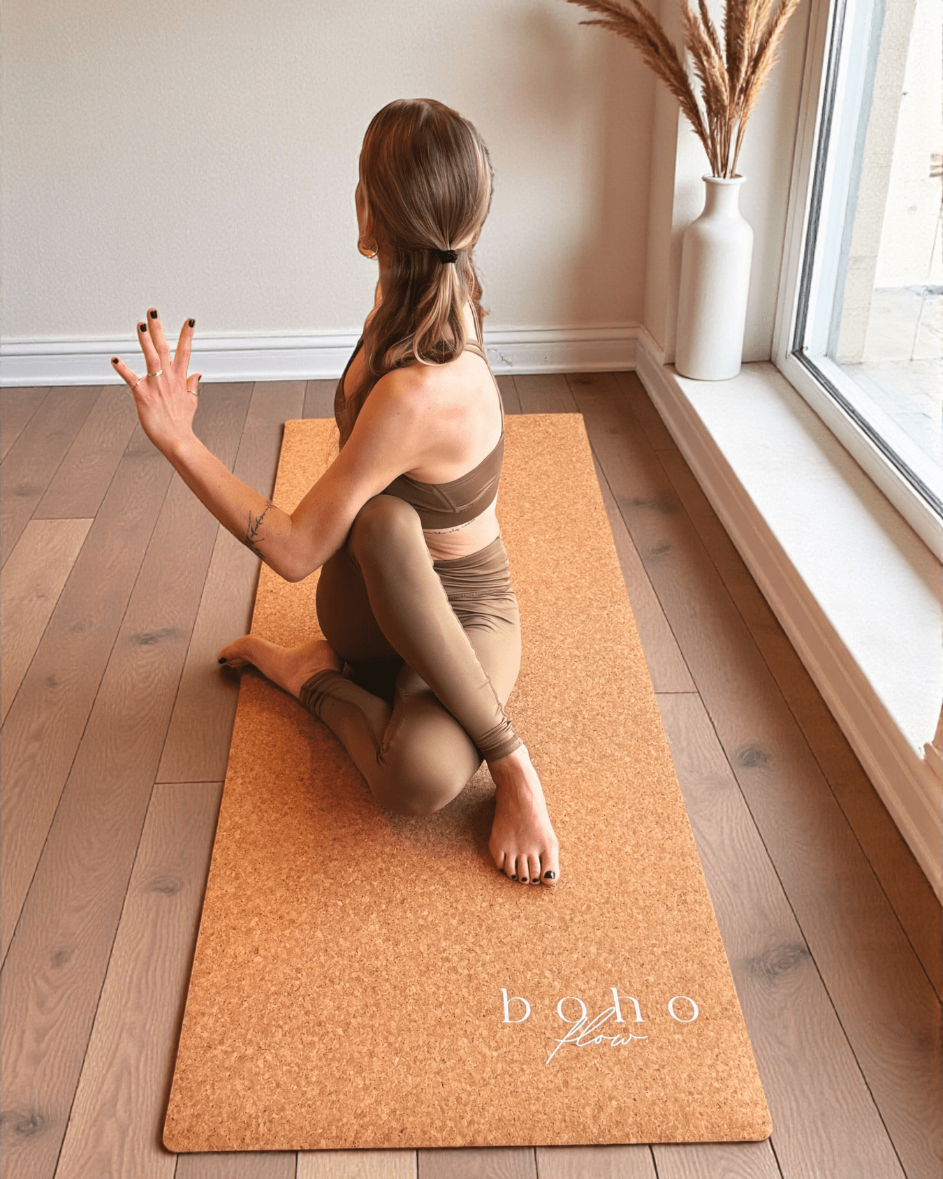 Person practicing yoga on a cork yoga  mat with 'boho flow' branding in a home setting.