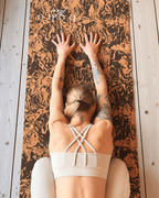 Girl practicing yoga on a coffee and cork yoga mat with 'Boho Flow' branding.