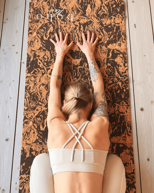 Girl practicing yoga on a coffee and cork yoga mat with 'Boho Flow' branding.