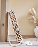 Macrame yoga mat bag on a wooden surface with a neutral background