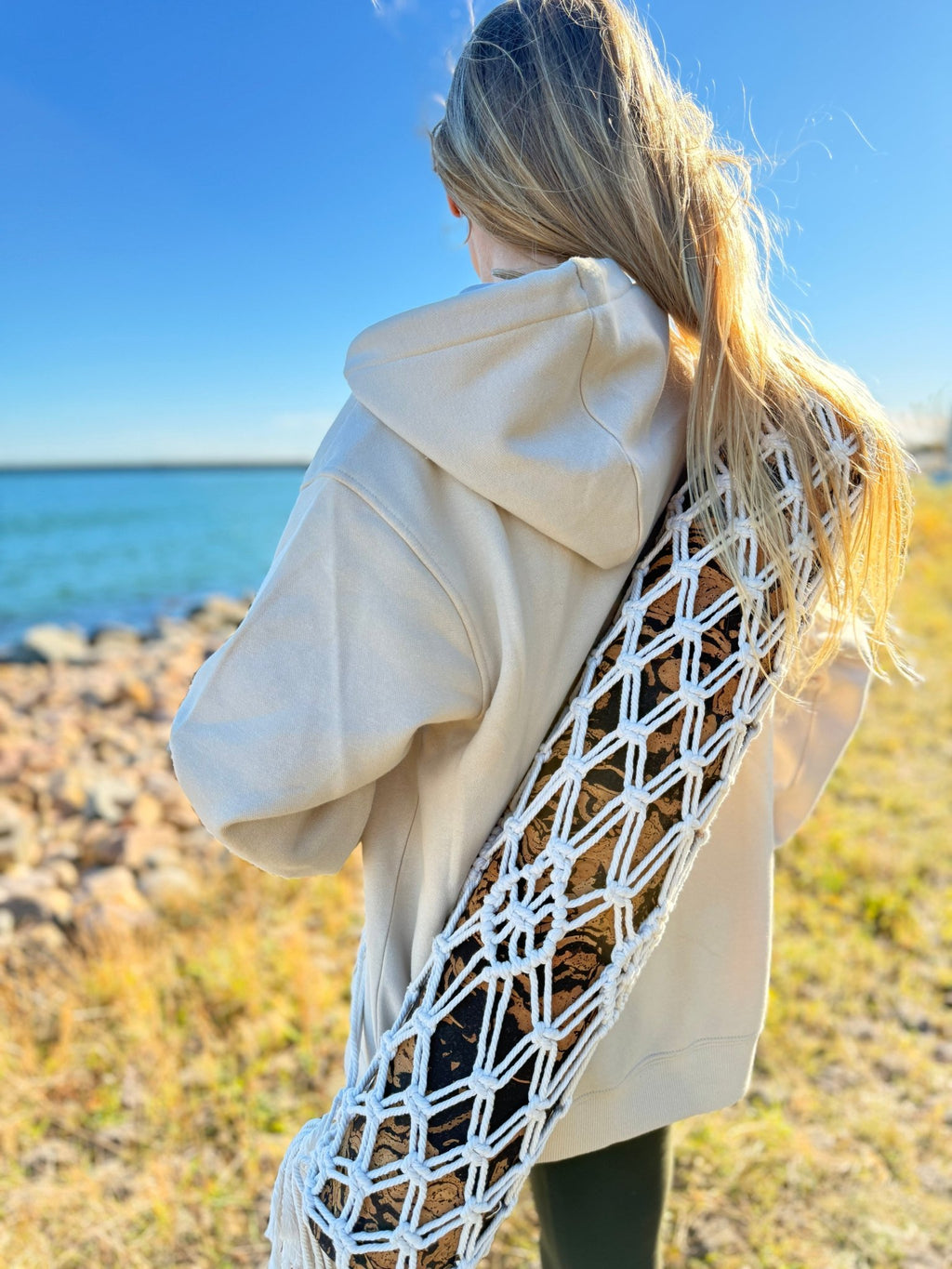 A Girl carrying a cork yoga mat inside a macrame boho yoga mat bag.