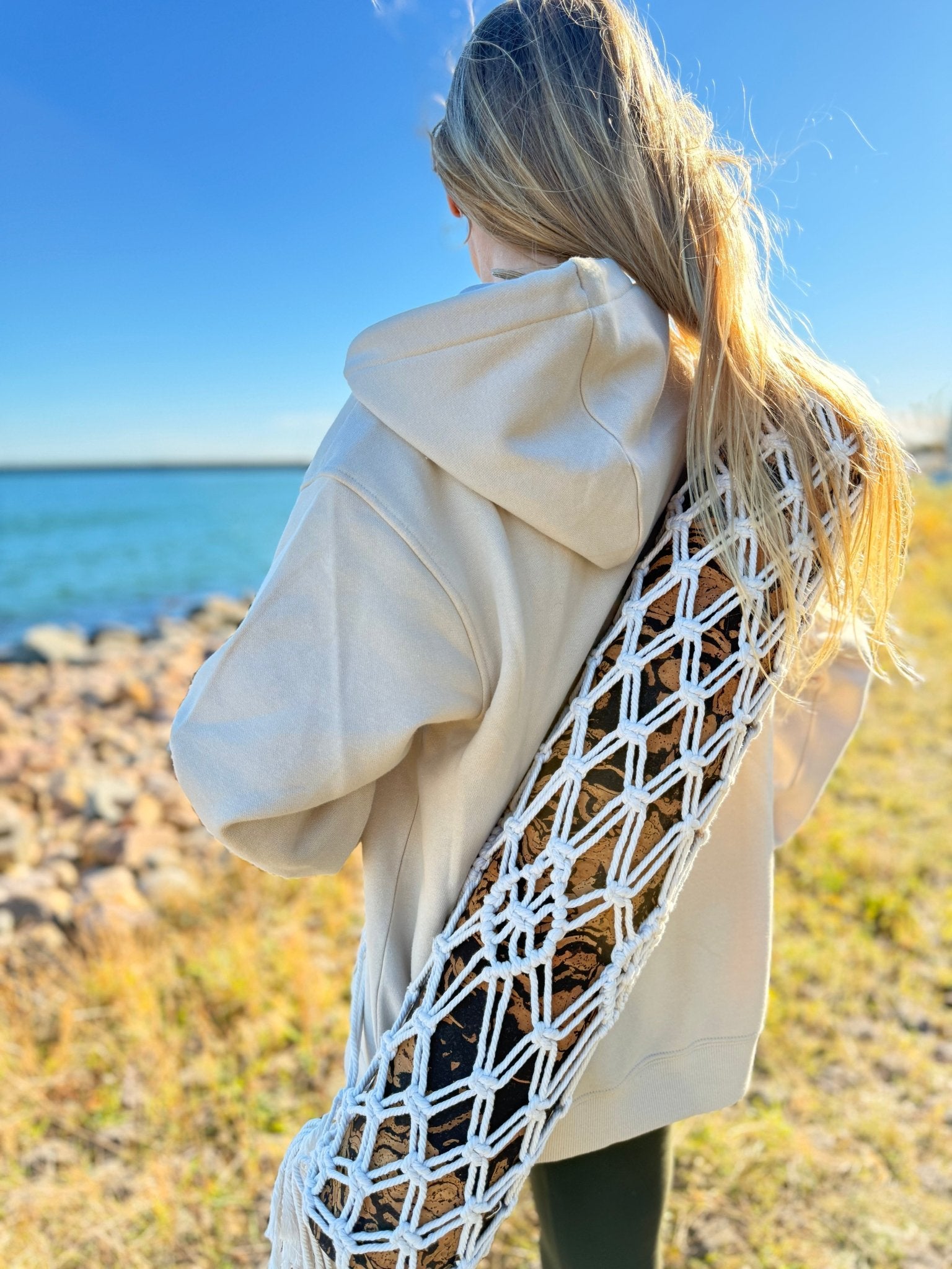 A Girl carrying a cork yoga mat inside a macrame boho yoga mat bag.