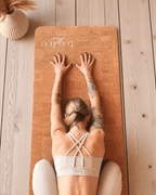 Person practicing yoga on a vegan leather cork yoga mat on a wooden floor.