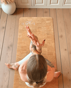 Person practicing yoga on a vegan leather cork mat with 'boho' branding in a home setting.