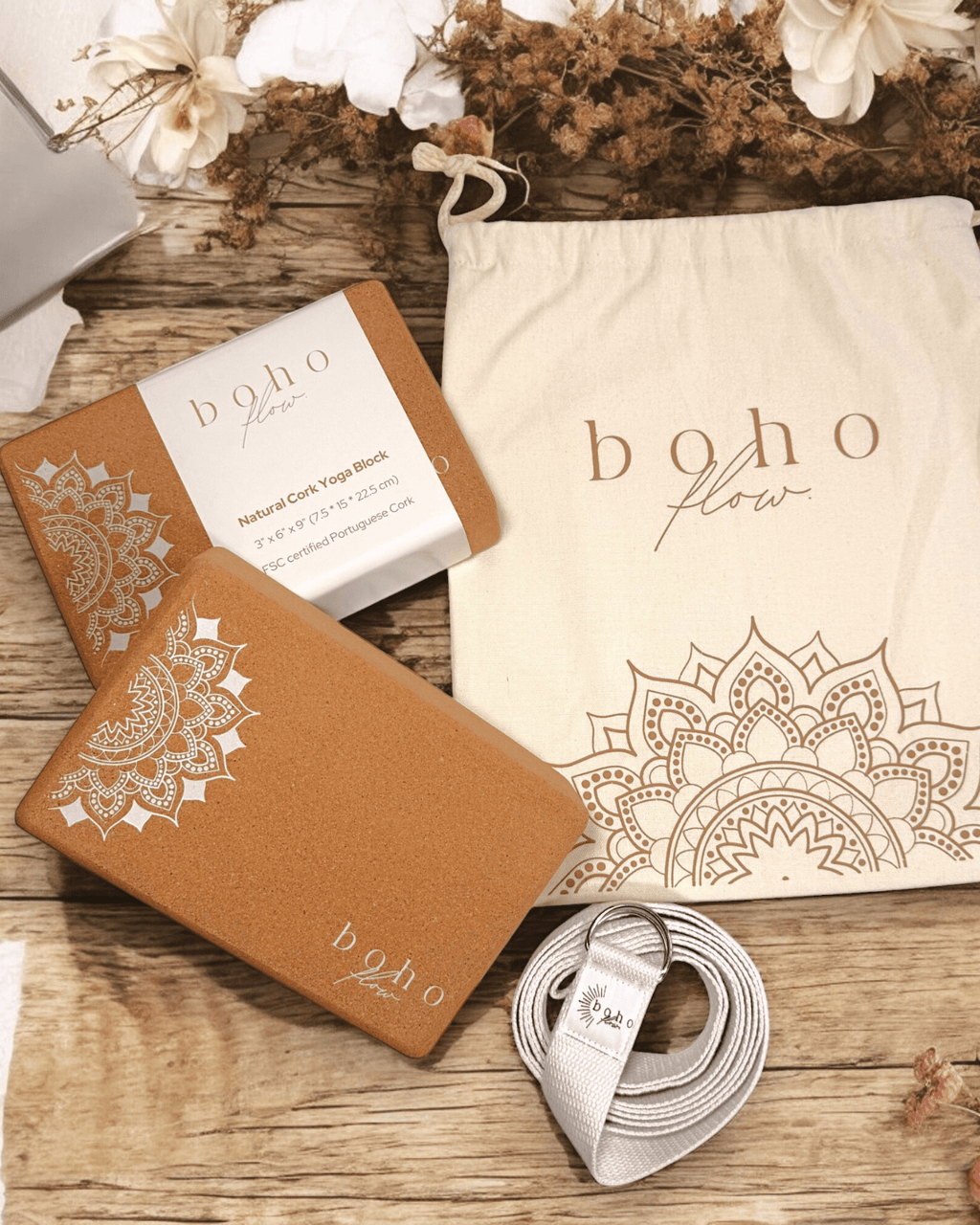 Boho Flow cork yoga blocks and yoga strap on a wooden surface with decorative flowers.