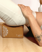 Person using a yoga block with 'boho flow' branding on a light wooden floor.