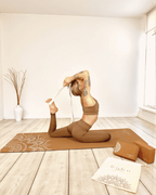 Person in a yoga pose on a cork yoga mat with 'Boho Flow' branding in a room with a white wall and 2 cork yoga blocks.