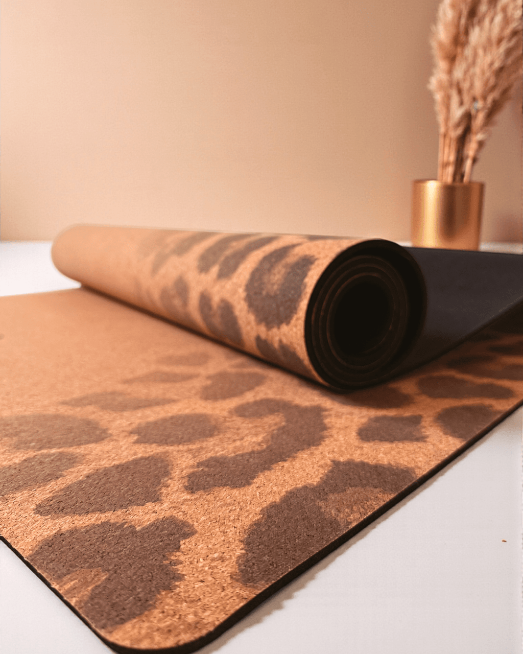 Rolled up cork yoga  mat with leopard print pattern on a white surface.