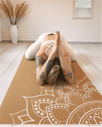 Person practicing yoga on a mandala patterned mat in a room with boho decor elements.