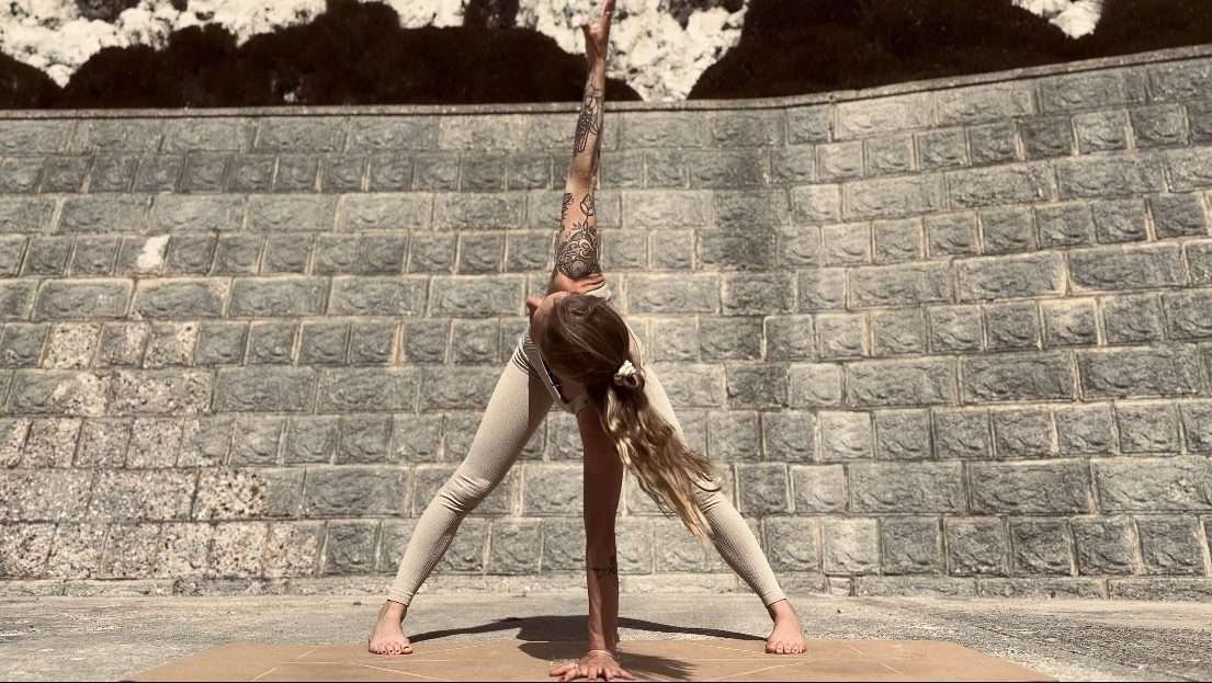 Showing a young woman performing a yoga pose outdoors on an eco-friendly cork yoga mat to demonstrate that eco-friendly yoga mats can be functional, chic, and sustainable. 